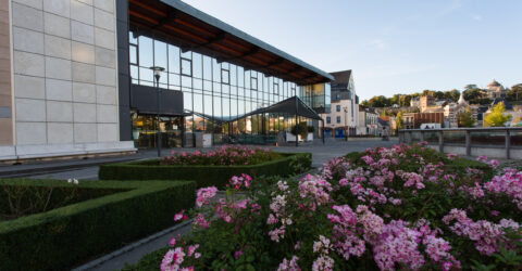 Photo exterieure du batiment de l'odyssée, avec au premier plan des fleurs roses